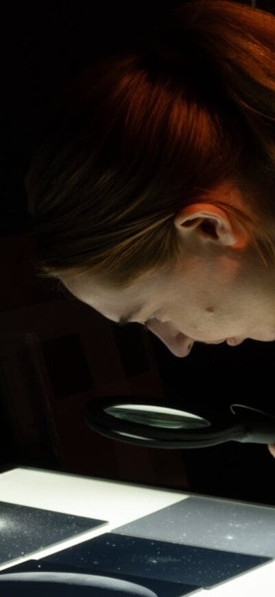 Person exploring glass plates with stars in Outer Space exhibition