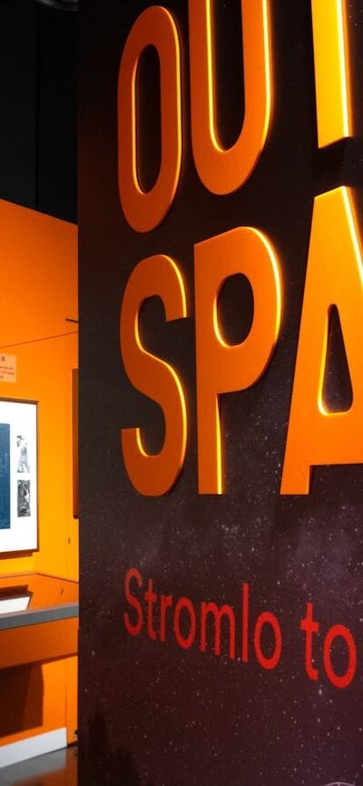 Outer Space exhibition wall with text and objects in distance