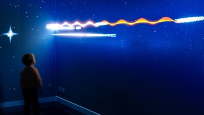 Gravitational Weave, a digital interactive representing the growth of our universe. A young person interacting with Gravitational Weave at Outer Space