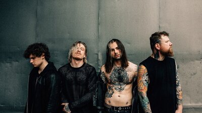 The four band members of Paleface Swiss against a wall looking to the side and to the camera