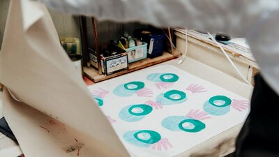 A photo of a textile print using stamps in round shapes in blue and pink