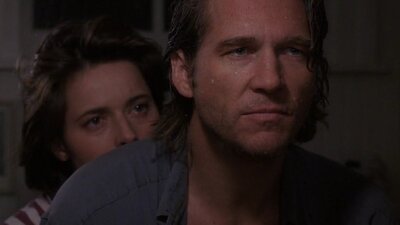 low lighting photo of man looking past camera and woman standing close behind his shoulder