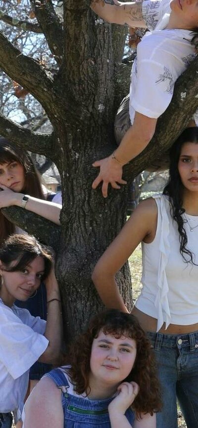 Picnic at Hanging Rock 5 young girls in denim and whites pose around a gnarly tree