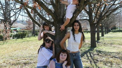 Picnic at Hanging Rock 5 young girls in denim and whites pose around a gnarly tree