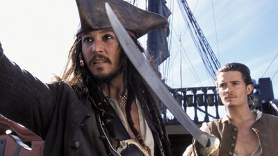 Pirate on a ship with another man pointing a sword to the left of the camera