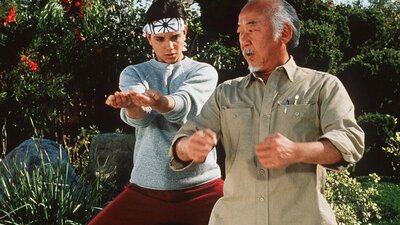 Still from The Karate Kid showing a man teaching a boy karate