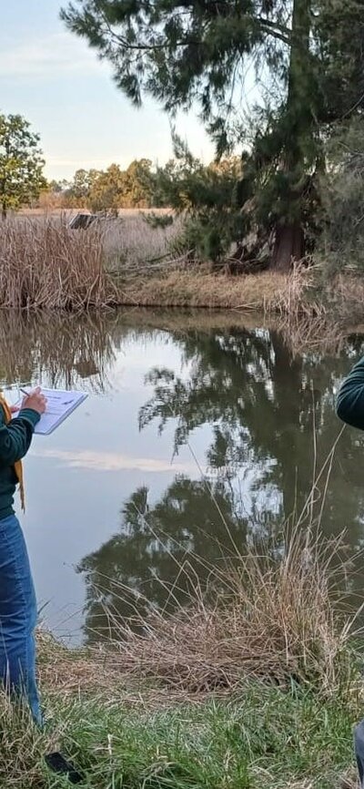 People participating in a Platypus survey two people by a river looking for platypus
