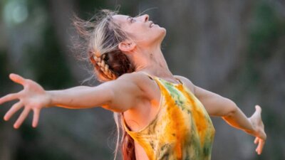 Woman looking up to the sky with her arms spread wide