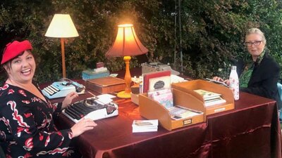Two women sitting with typewriters and stationery