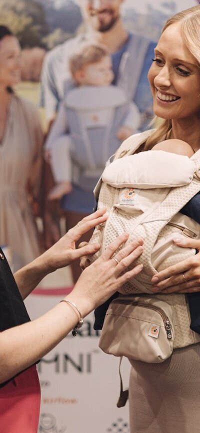 Babywearing expert is explaining pregnant woman how to wear baby carrier