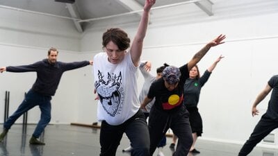 A group of people in the middle of a movement, lunging with their arm up and looking down.