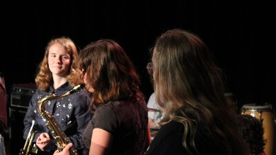 close up of girls on stage, one playing saxophone
