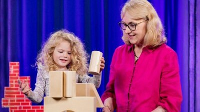 Female child playing with building blocks next to her grandmother