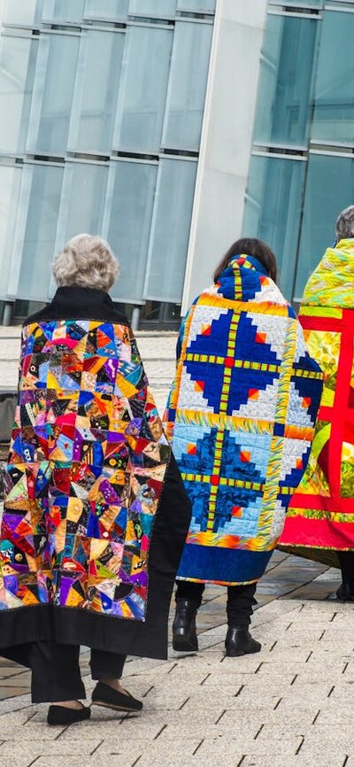 Canberra Quilters walking with colourful quilts over their shoulders through Civic Square