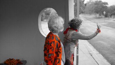 Rapt in felt 2025 Hailing the bus Two women dressed in orange felt at a bus stop in Canberra.