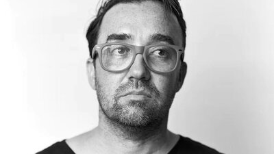 Gabriel Clark A sepia portrait of a man with glasses, looking slightly upward and to the side.