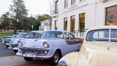 Photograph of pastel coloured classic Holden cars parked on display in front of NAA canberra