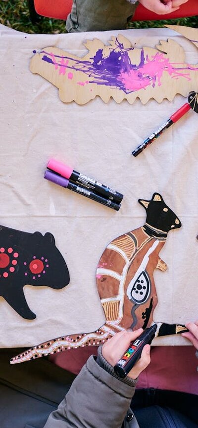 Children decorating wooden animal cutouts with colorful markers during an art activity at a table