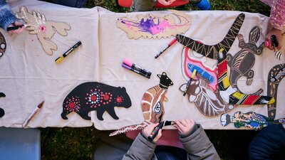 Children decorating wooden animal cutouts with colorful markers during an art activity at a table