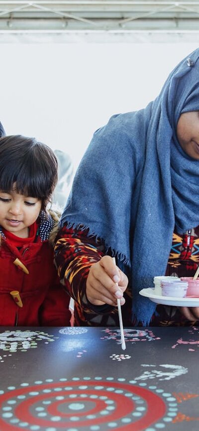 Family of four painting on large canvas decorated with colourful patterns and handprints
