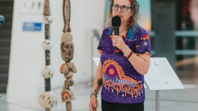 Woman dressed in aboriginal polo shirt standing in front of stone sculptures