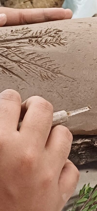 Hands working on shaping a traditional coolamon vessel