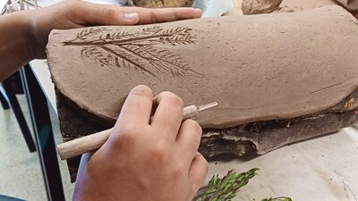 Hands working on shaping a traditional coolamon vessel