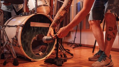 microphone being placed in front of a bass drum of a drum kit