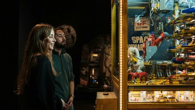 Adult couple enjoying observing a claw machine exhibit in RELICS