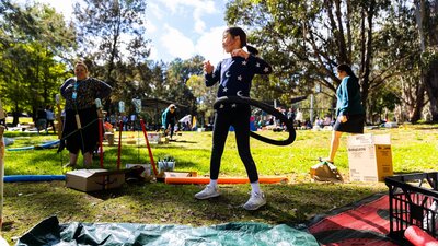 A young girl uses a bike tire as a hulla hoop in a park.