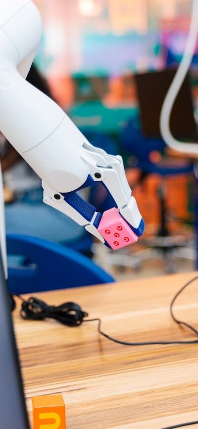 A robotic arm picks up a pink dice.