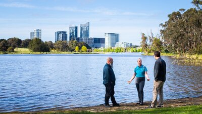 Three researchers talk amongst themselves at the banks of Lake Burley Griffin.