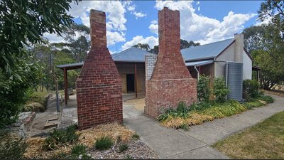 Heritage cottage building with large outdoor chimneys in foreground.