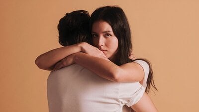 A woman is hugging another person who is facing away from the camera