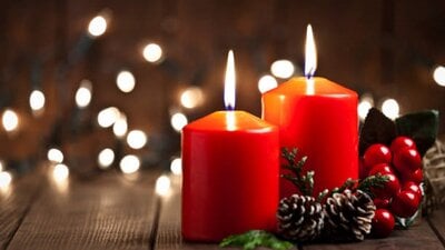 Two red candles burning surrounded by Christmas decorations