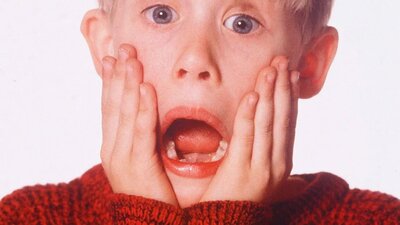 Young boy with mouth open holding his face in shock