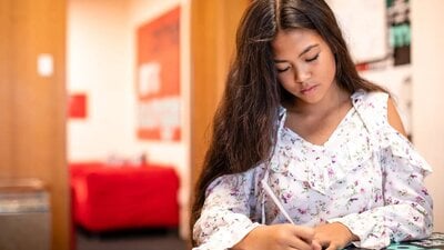 A girl sitting down and writing