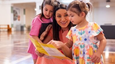 A mother and her young daughters looking at the museum map