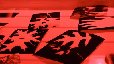 An image of black and white prints made in the darkroom floating in a water bath