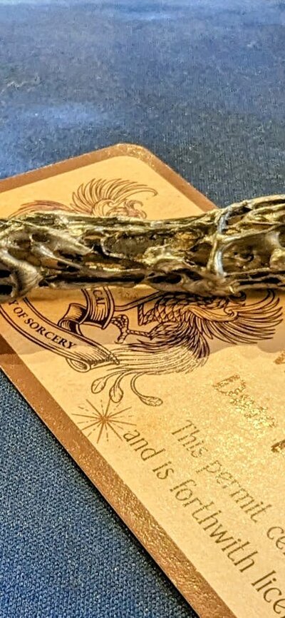 Photo of a handmade wand on a table with a completed wand license.