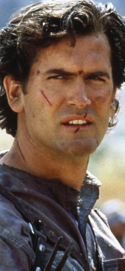 Army of Darkness (1992) Man looks past camera with cuts on his face, dressed ready for battle