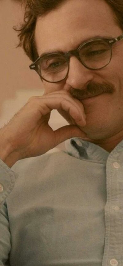 Man with moustache and glasses looking content smiling and looking down