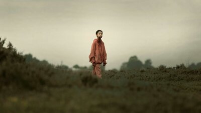 Young child with shaved head stands in isolated surrounds with blood around mouth