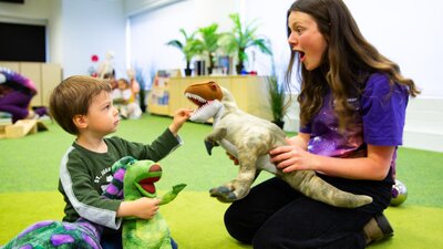 A young boy and a Questacon facilitator play with dinosaurs at Science Time