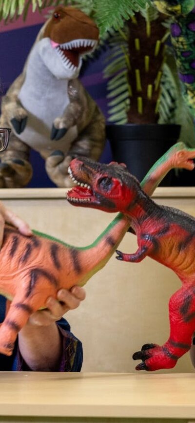 A young child and their grandma play with dinosaurs at Science Time