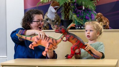 A young child and their grandma play with dinosaurs at Science Time
