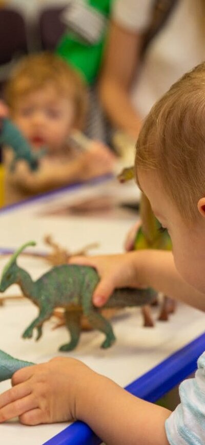 A young boy plays with toy dinosaurs at Science Time