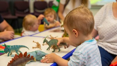 A young boy plays with toy dinosaurs at Science Time