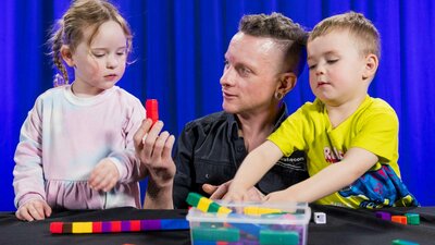 Two children and a man explore patterns using coloured blocks