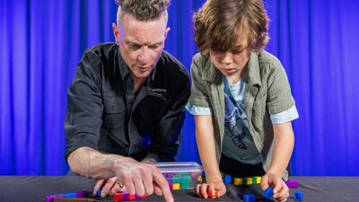 A man and a boy explore patterns using coloured blocks